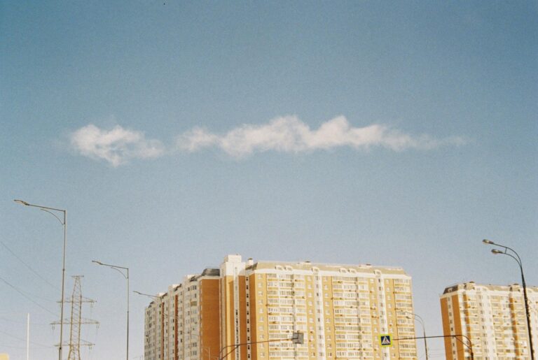 Low angle view of modern condominium against a clear blue sky, showcasing urban architecture.